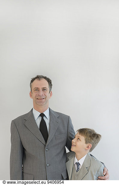 Father holding his son in his arm against white background  smiling