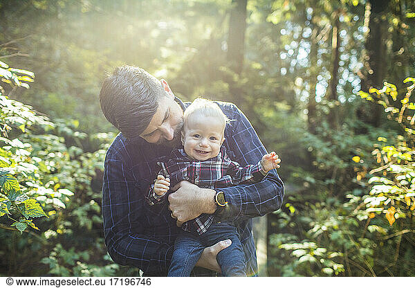 Father holding  loving young son outdoors.