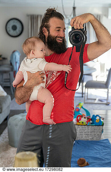 Father holding son while taking photograph.