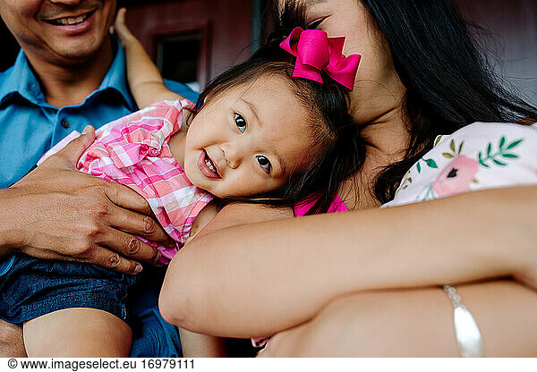 Father holding sweet young asian girl with pink bow in hair