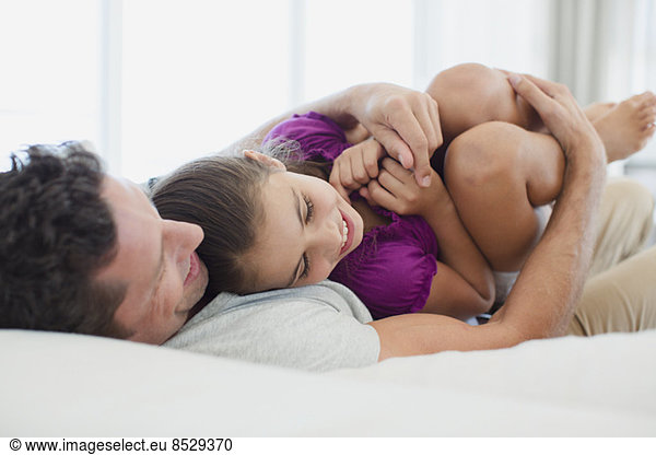 Father hugging daughter on bed