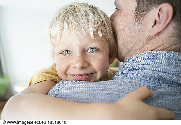 Father kissing and hugging son at home