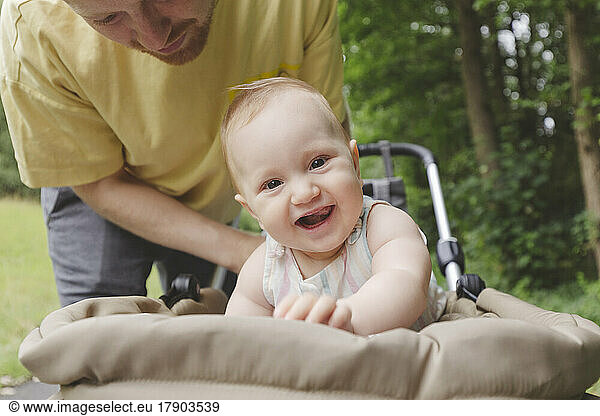 Father picking up baby girl from stroller at park