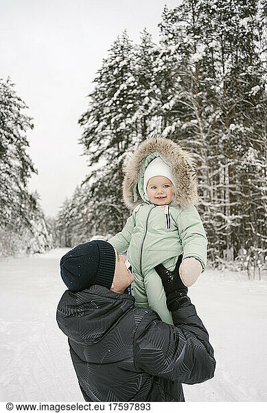 Father picking up cute daughter in winter