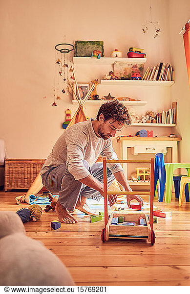 Father picking up toys in childâ€™s bedroom