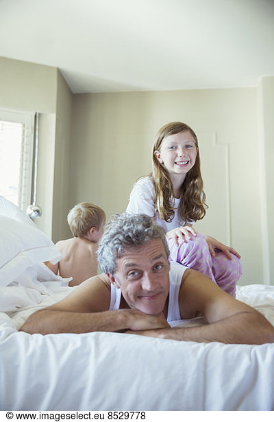 Father playing with children on bed
