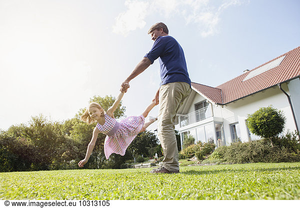 Father playing with daughter in garden