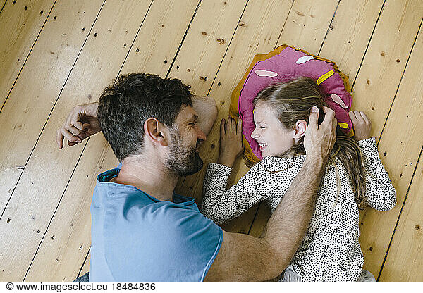 Father playing with daughter lying on floor at home