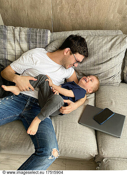 father playing with his son while resting from gadget