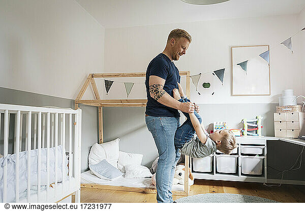 Father playing with son in bedroom at home