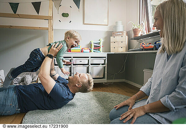 Father playing with son while mother sitting in bedroom