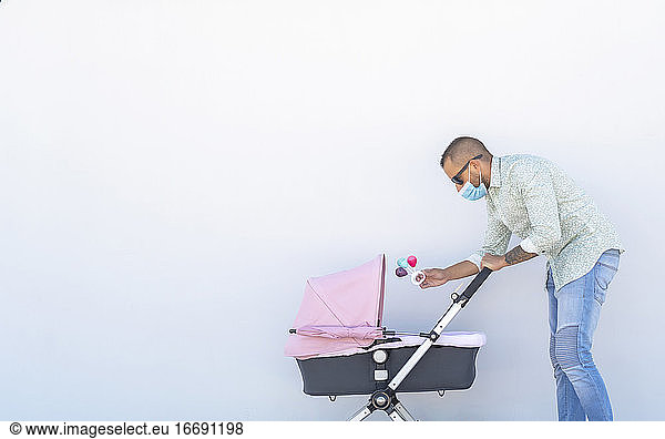 father playing with the rattle with his baby in his stroller