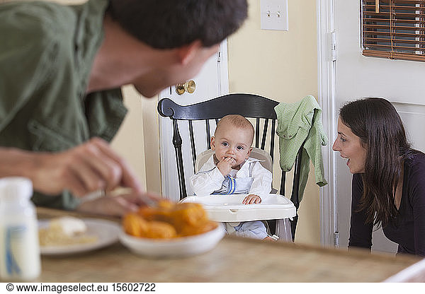Father preparing baby's meal and mother watching