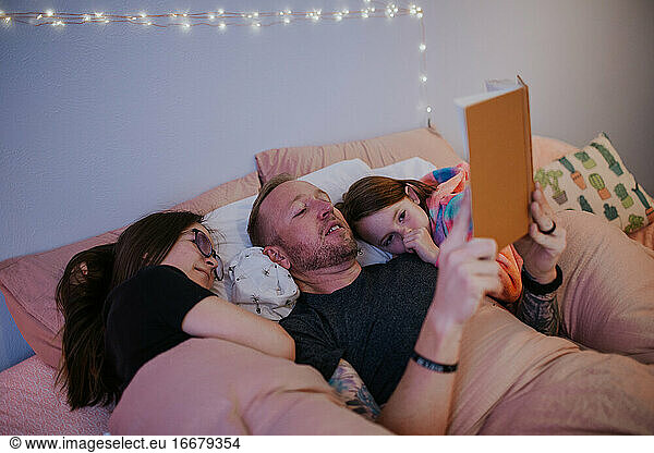 Father reading and snuggling kids in bed