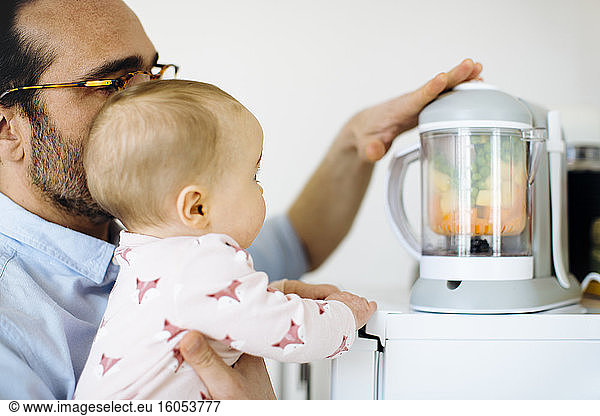 Father showing his baby girl a mixer