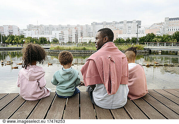 Father sitting with children on pier in city