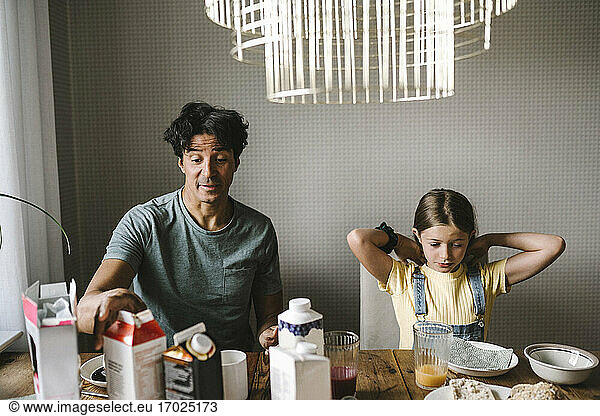 Father sitting with daughter while having breakfast at home