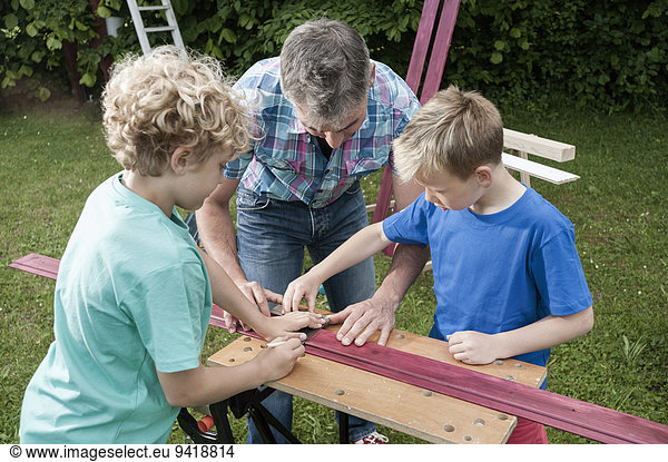 Father sons working garden building wood