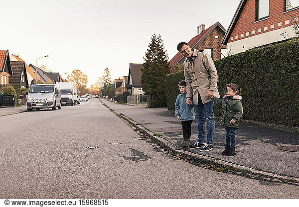 Father standing with children on sidewalk during autumn