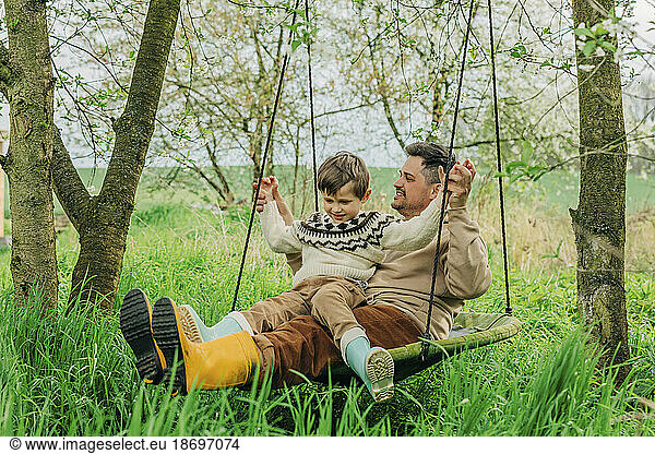 Father swinging with son in garden