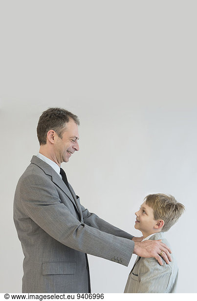 Father talking to son with hands on his shoulder  smiling