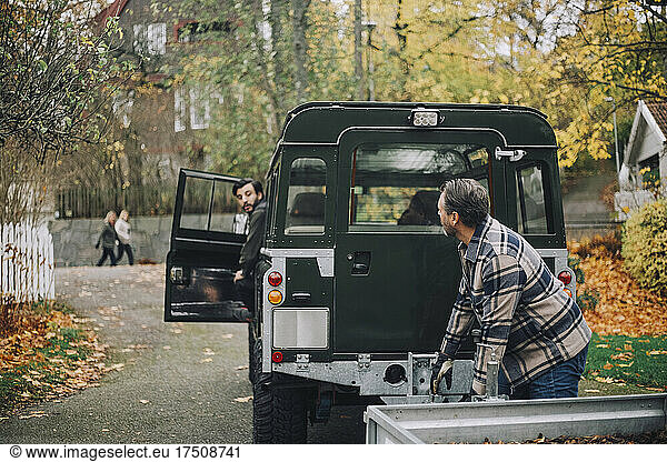 Father talking with son sitting in sports utility vehicle