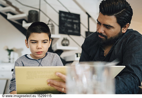 Father teaching autistic son while sitting in living room at home