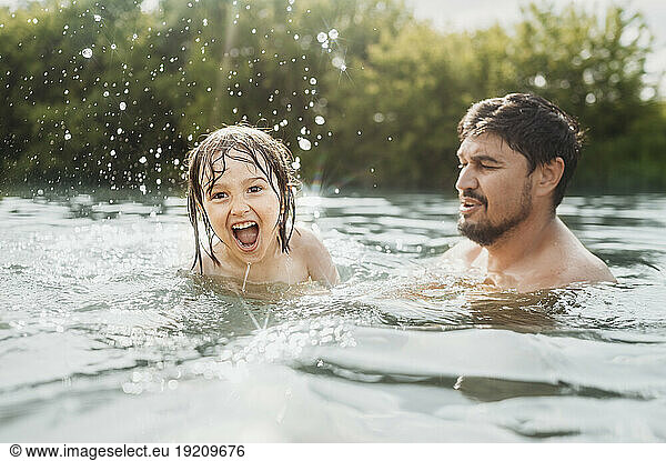 Father teaching swimming to son in river