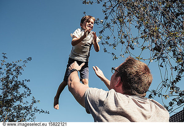 Father throwing little son up in air