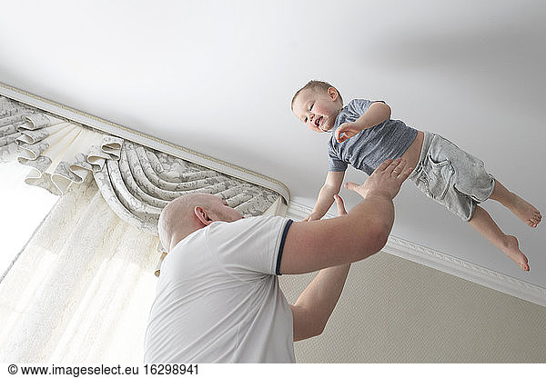 Father throwing son in the air at home