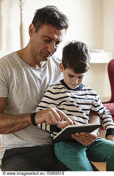 Father using tablet with son at home