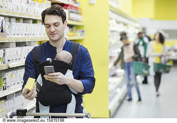Father with baby scanning label on box in supermarket