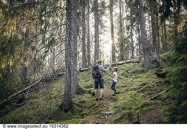Father with backpack talking to daughter in forest