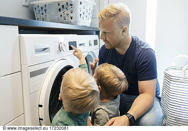 Father with children doing laundry chores in utility room