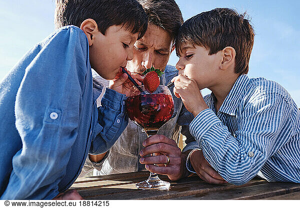 Father with children drinking juice on sunny day