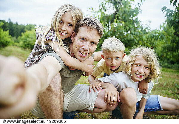 Father with children taking selfie in garden