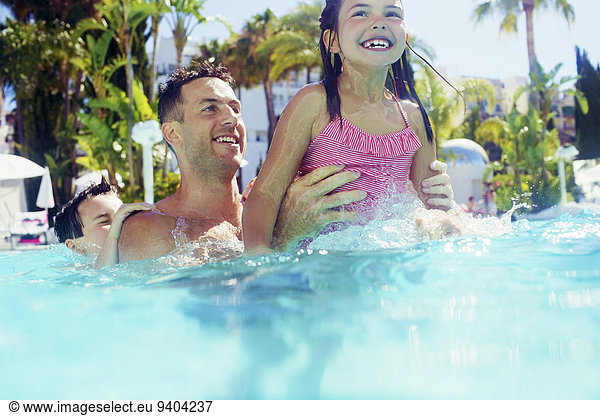 Father with daughter and son playing in swimming pool
