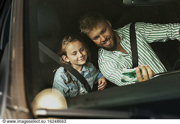 Father with daughter in car taking selfie
