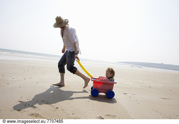 Father with daughter in wagon on beach