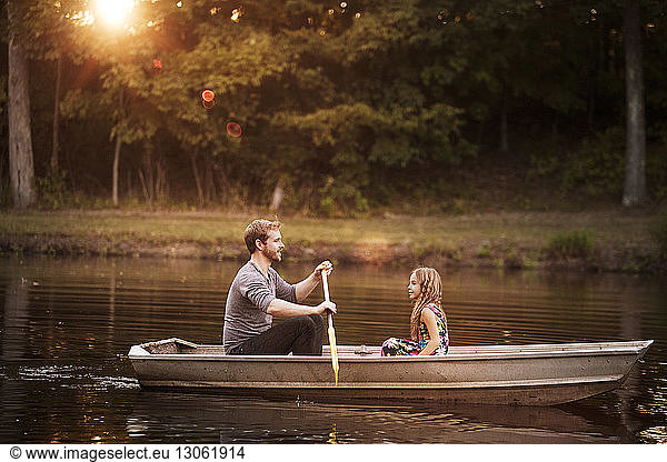 Father with daughter oaring boat in lake