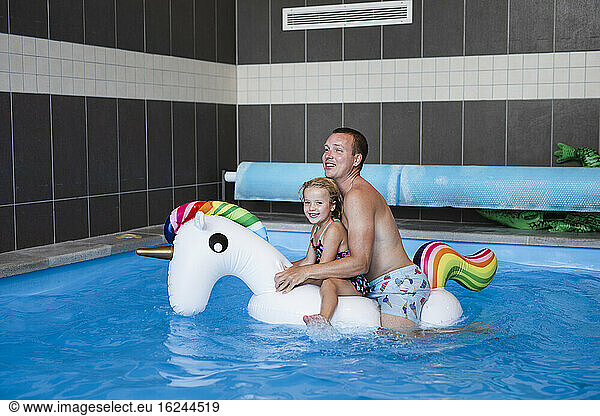Father with daughter on inflatable unicorn