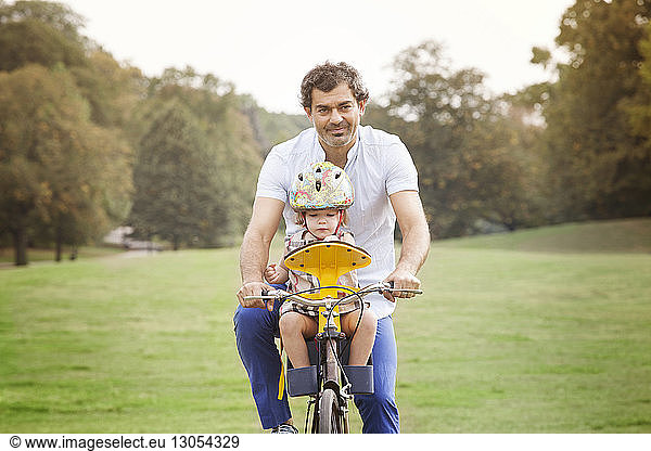 Father with daughter riding bicycle at park