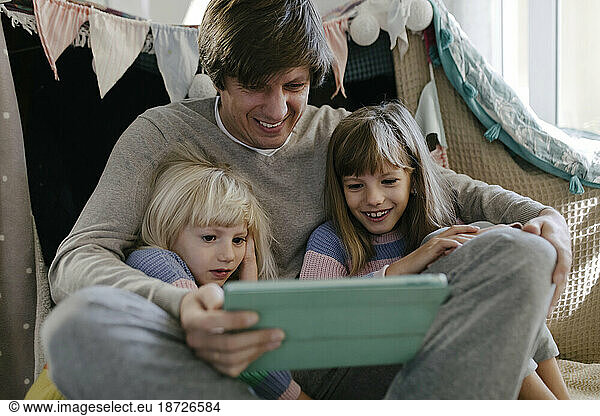 Father with daughters watching video on tablet computer