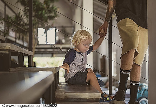 Father with little boy walking on stairs at home