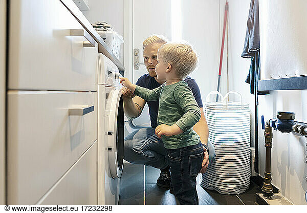 Father with son doing laundry chores in utility room