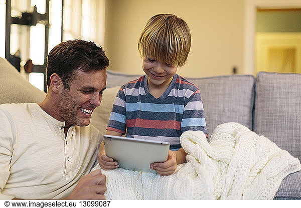Father with son using tablet computer while sitting at home