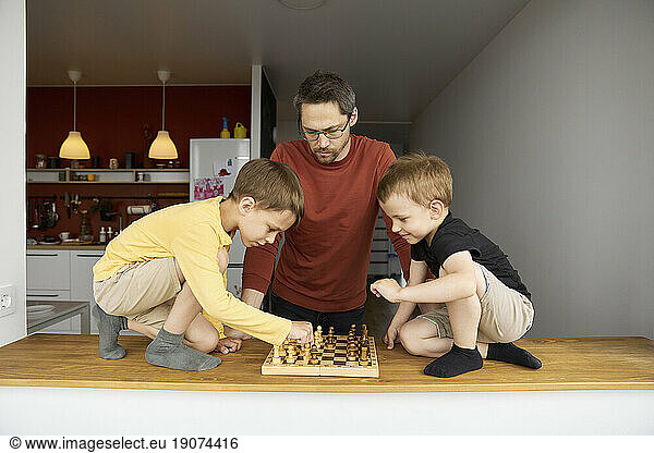 Father with sons playing chess at home