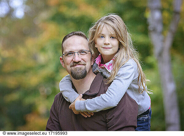 Father with young blond daughter hugging.