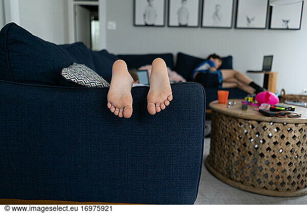 feet and toes of child laying on couch with brother in background