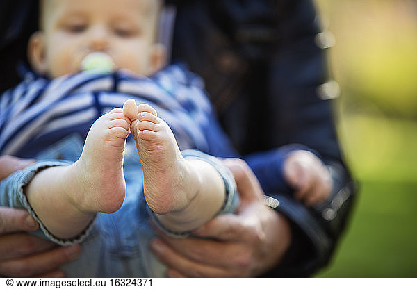 Feet of baby boy holding by his father